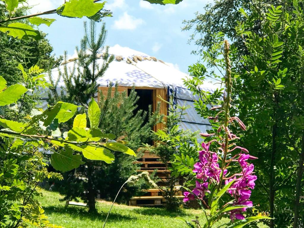 a thatch roofed yurt in a garden with flowers at Eco Yourte Les Airelles in Saint-Anthème