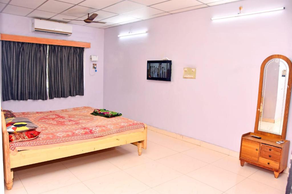 ein Schlafzimmer mit einem Bett, einem Spiegel und einer Kommode in der Unterkunft Lakshmi cottage in Mahabalipuram