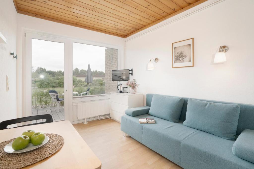 a living room with a blue couch and a table at Blankwasserweg 131 Lensterstrand Oase Bungalow 5 in Lenste