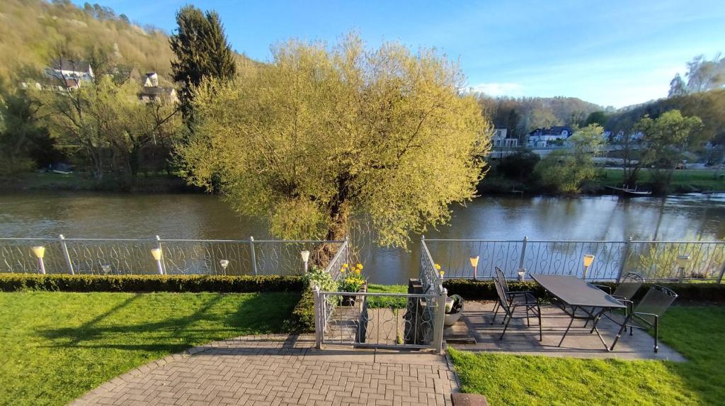 a table and chairs next to a tree next to a river at Ferienwohnung Mila in Obernhof