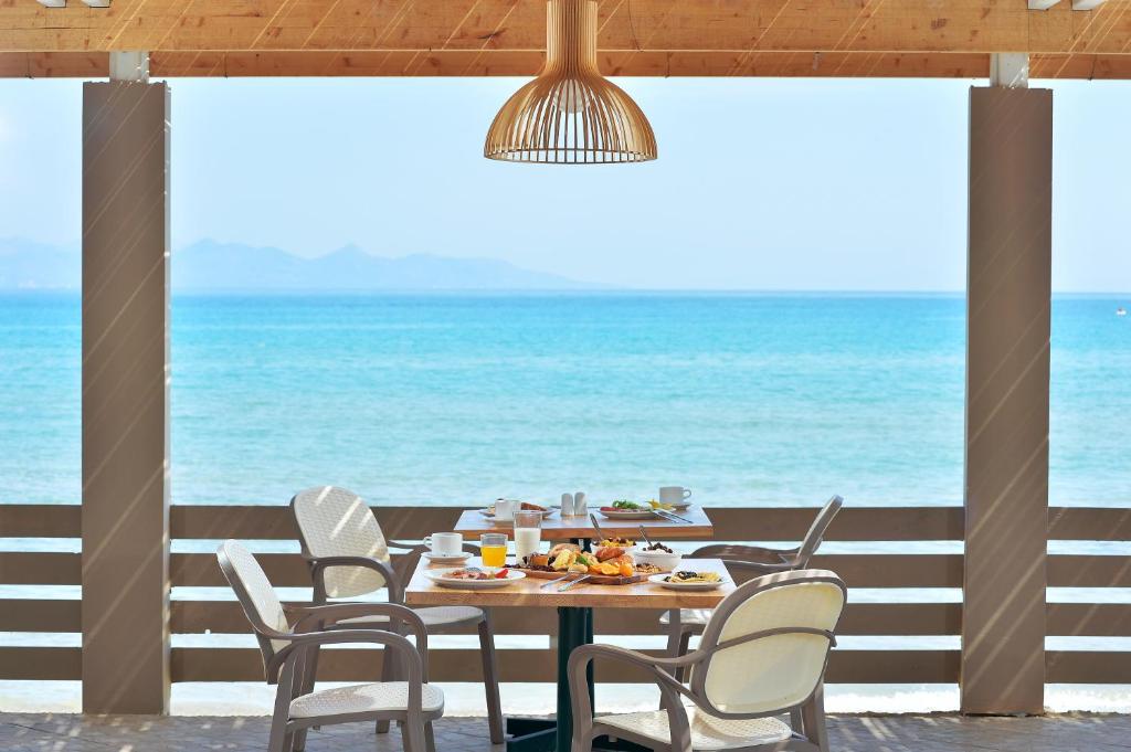 een tafel en stoelen met de oceaan op de achtergrond bij Alykanas Beach Grand Hotel by Zante Plaza in Alikanas