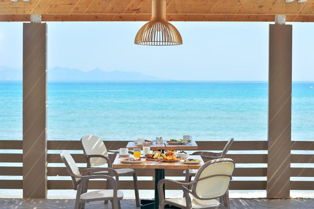 einen Tisch und Stühle mit Meerblick im Hintergrund in der Unterkunft Alykanas Beach Grand Hotel by Zante Plaza in Alikanas