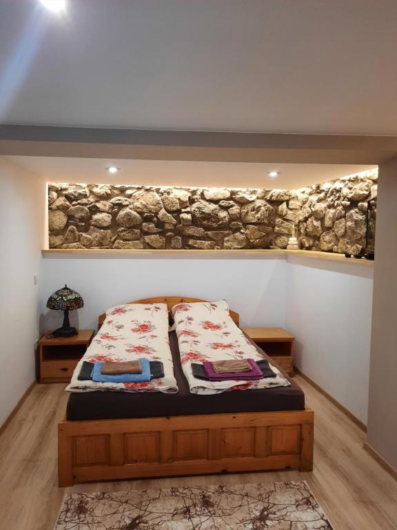 a bedroom with a bed and a stone wall at Къща за гости Ози in Ovchartsi