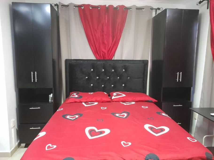 Una cama con una colcha roja con corazones. en Apartamento ideal, en Santo Domingo