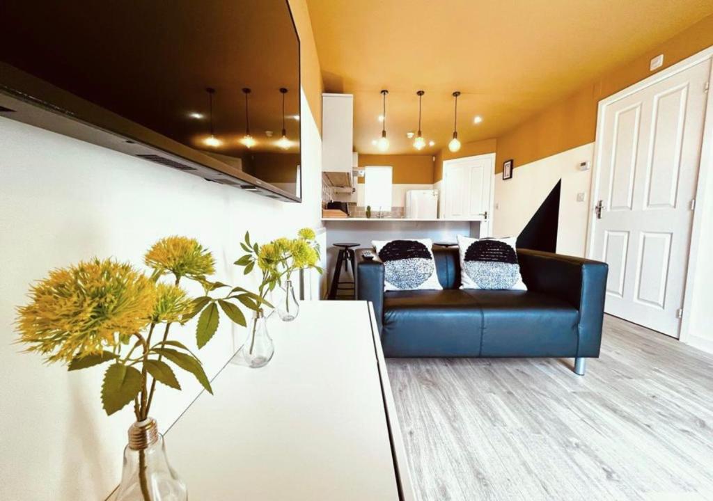a living room with a blue couch and a kitchen at She's Electric in Blandford Forum