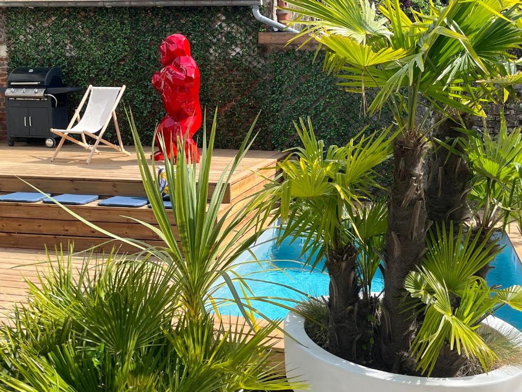 une statue rouge dans un jardin à côté de quelques plantes dans l'établissement Aux remparts de Montreuil, à Montreuil-sur-Mer