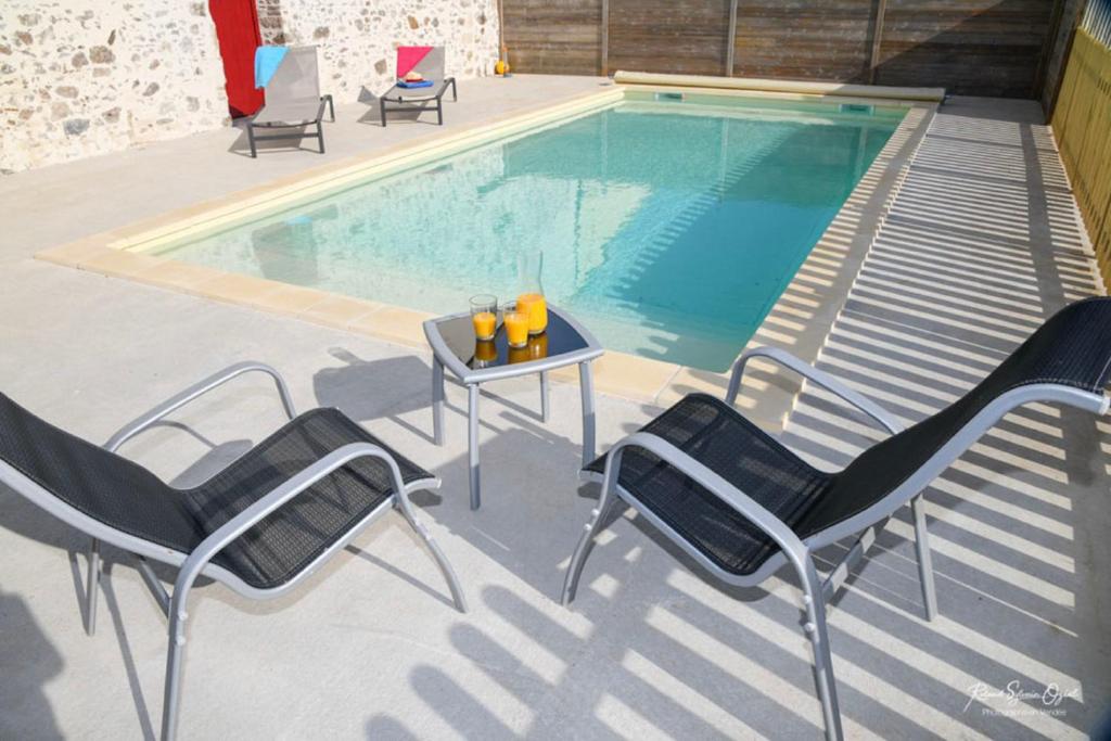 a table and chairs next to a swimming pool at Domaine de La Courillère in Le Boupère