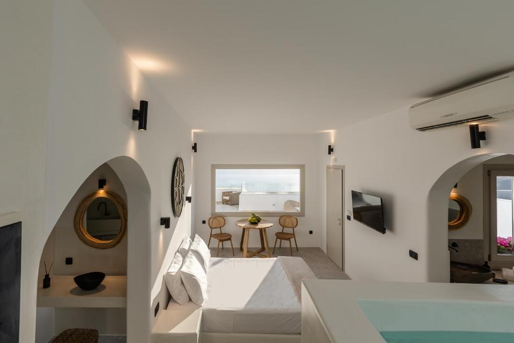 a white bedroom with a bed and a table at Suenos De Vida Lux Suite in Firostefani