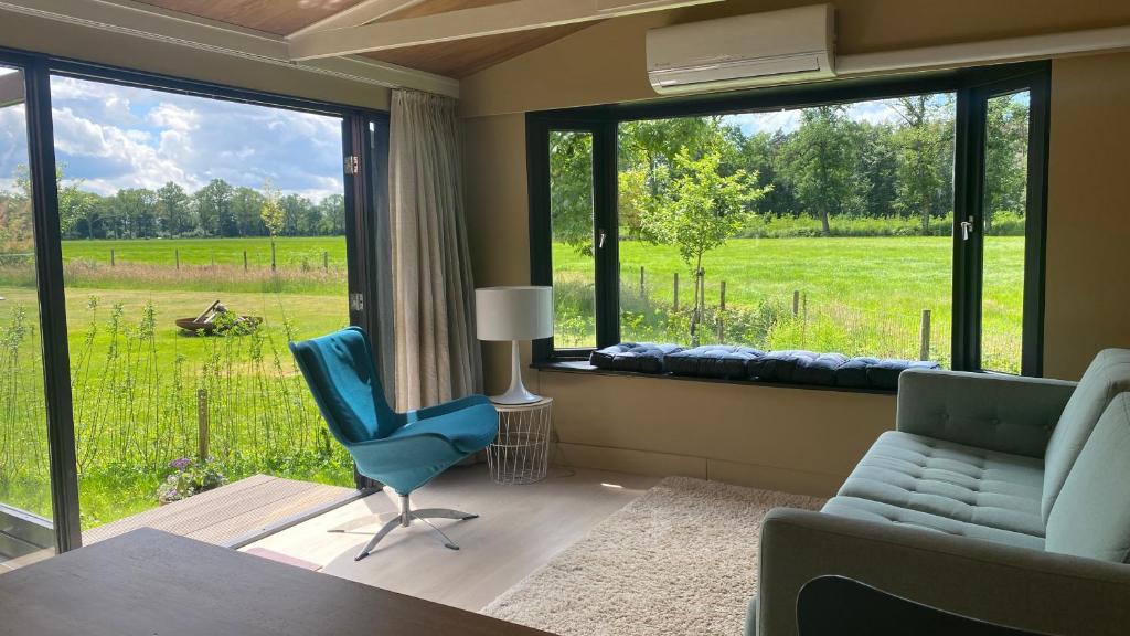 een woonkamer met een groot raam met uitzicht op een veld bij Chalet "naast de Schoppe" in Aalten