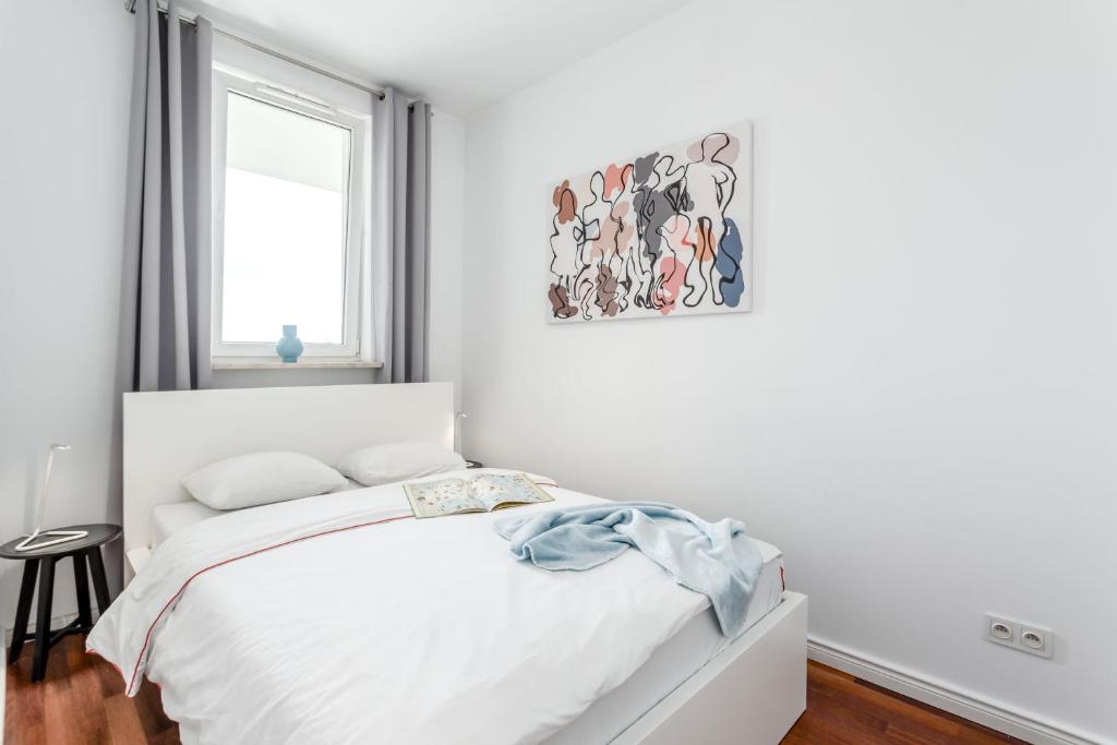 a white bedroom with a bed and a picture on the wall at Chill Apartments Mokotow Business Park in Warsaw