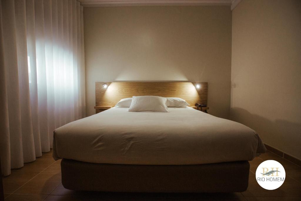 een slaapkamer met een groot wit bed in een kamer bij Rio Homem in Terras de Bouro