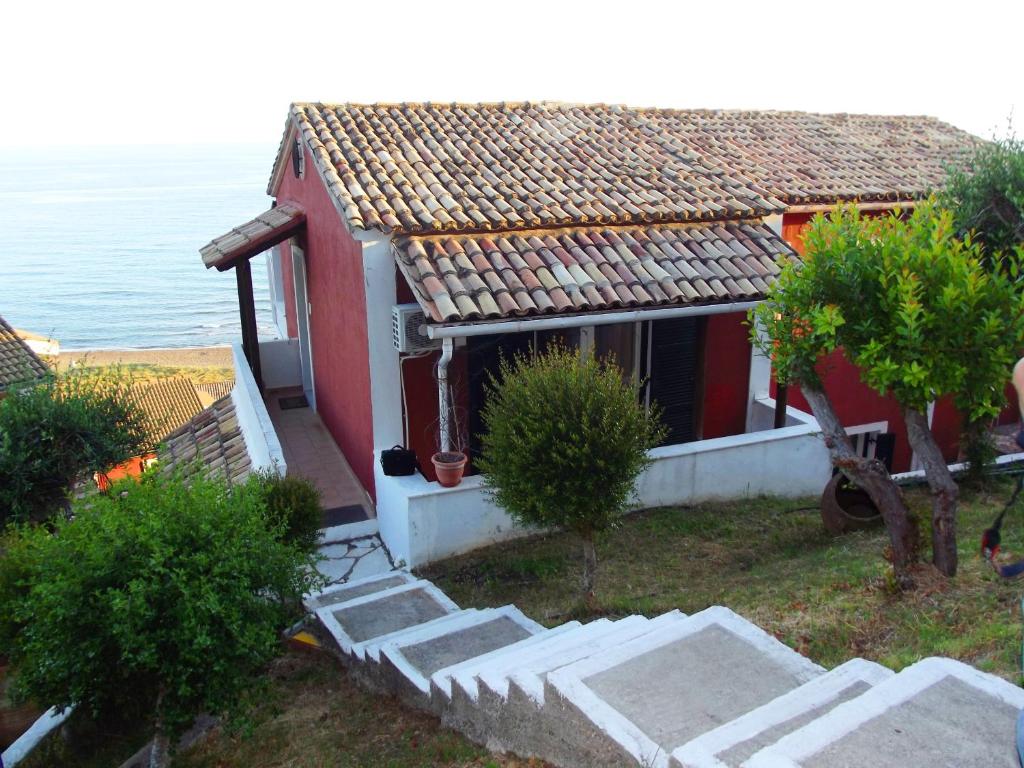 een rood-wit huis met een trap naast de oceaan bij Adriatic View Villa in Glyfada