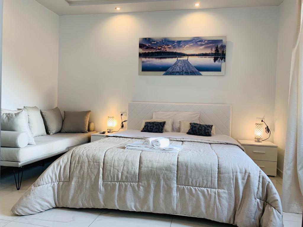 een slaapkamer met een groot bed en een bank bij Dolomia Gioele in Molveno