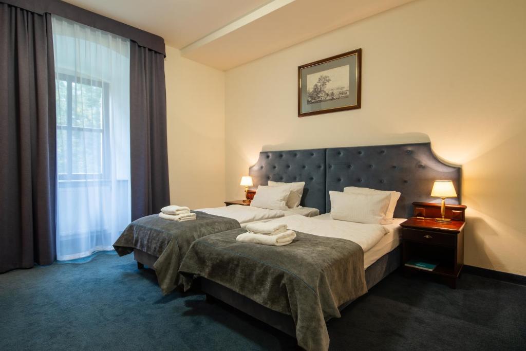 Cozy hotel room with twin beds, soft lighting, and elegant decor.