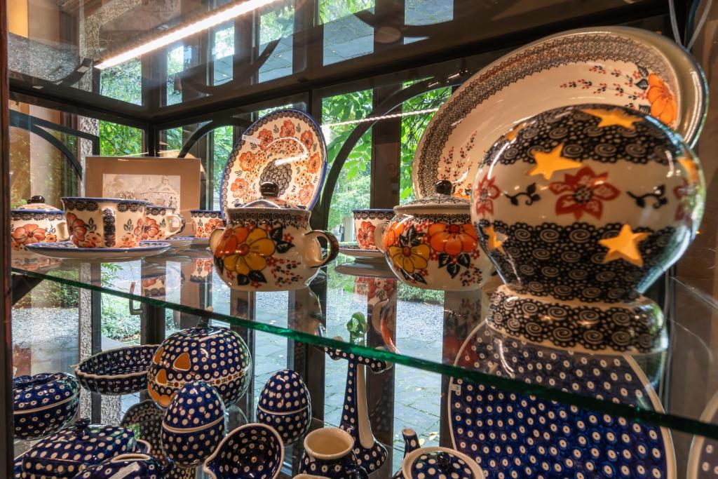 Colorful ceramic dishes displayed in a glass cabinet with outdoor greenery visible.