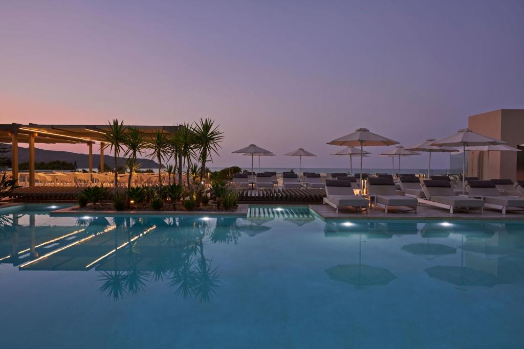 una piscina con sedie e ombrelloni di Atlantica Amalthia Beach Hotel - Adults Only ad Agia Marina Nea Kydonias
