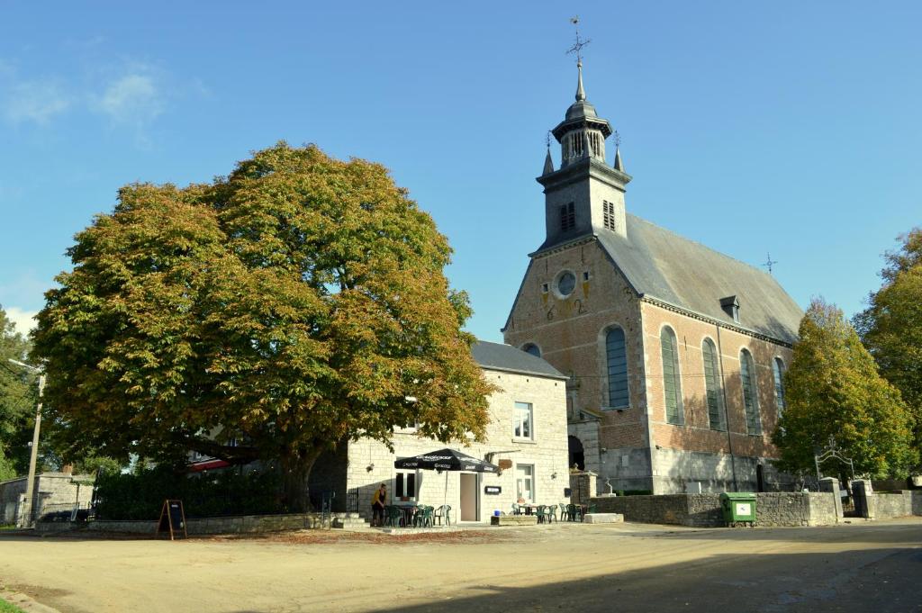 uma igreja com uma torre com uma árvore em frente em B&B Le Vieux Marronnier em Foy-Notre-Dame