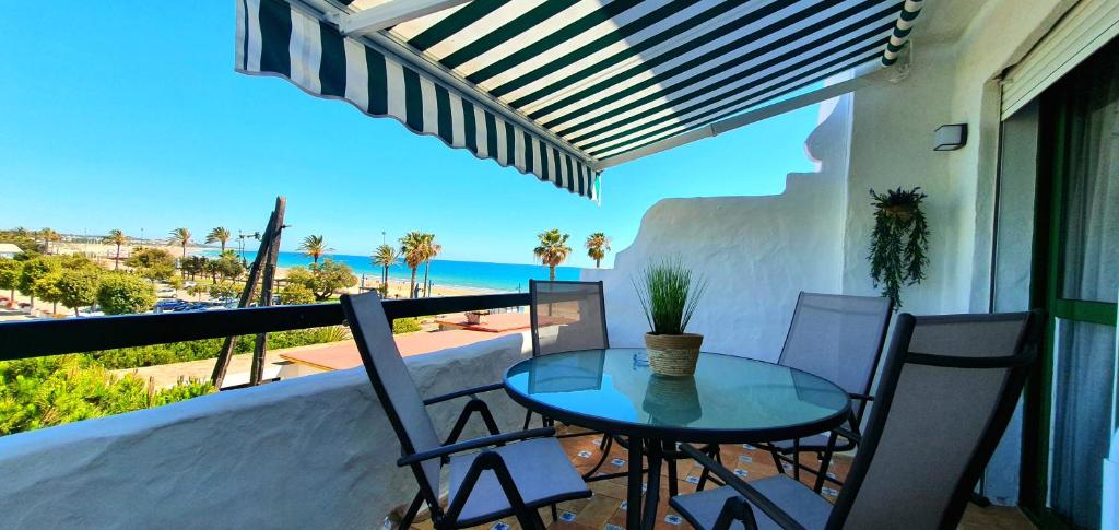 una mesa y sillas en un balcón con vistas al océano en Apartamento a pie de playa La Barrosa, en Chiclana de la Frontera