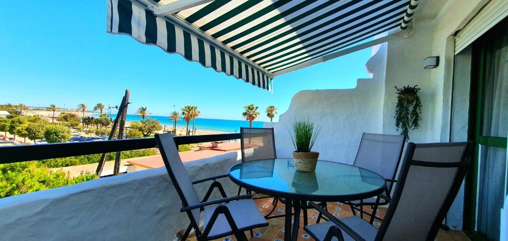 una mesa y sillas en un balcón con vistas al océano en Apartamento a pie de playa La Barrosa en Chiclana de la Frontera