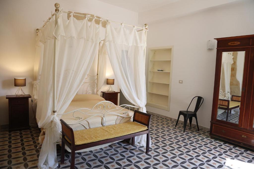 sypialnia z łóżkiem z baldachimem i krzesłem w obiekcie Charme in centro - Tourist rental w mieście Agrigento