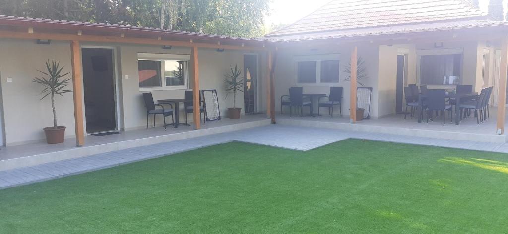 a patio with a green lawn in front of a house at Borti Apartman in Zamárdi