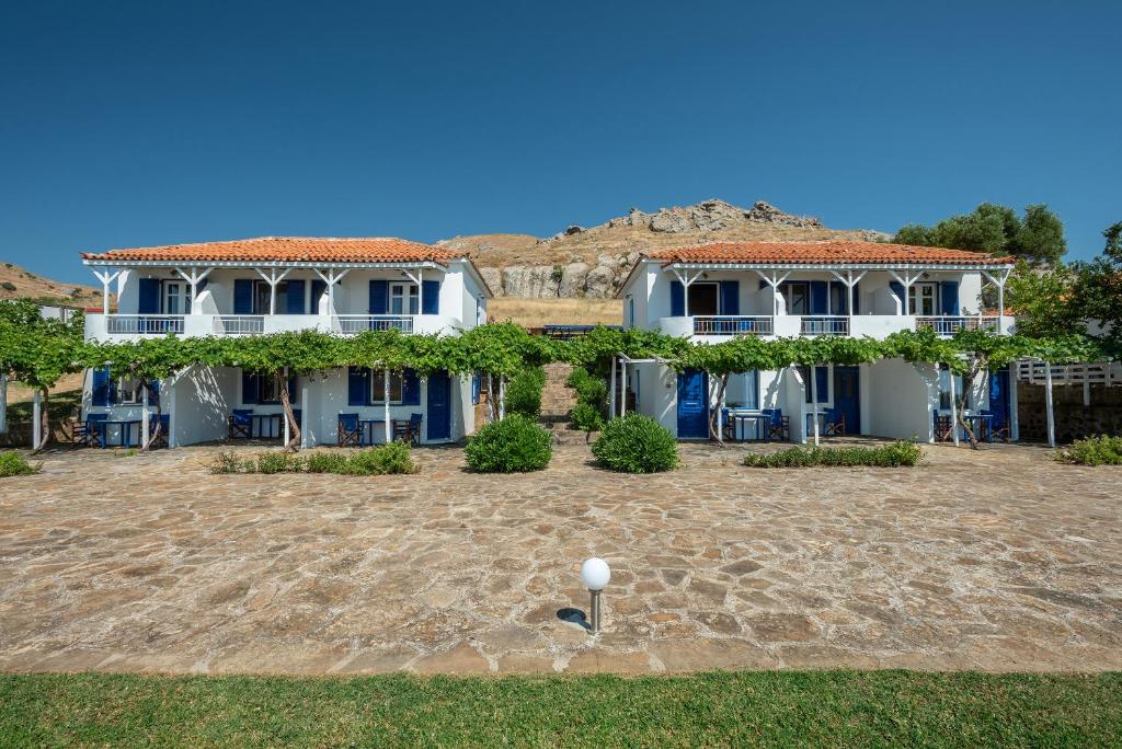 a large white house with a large yard at Sunset Hotel in Agios Ioannis Kaspaka