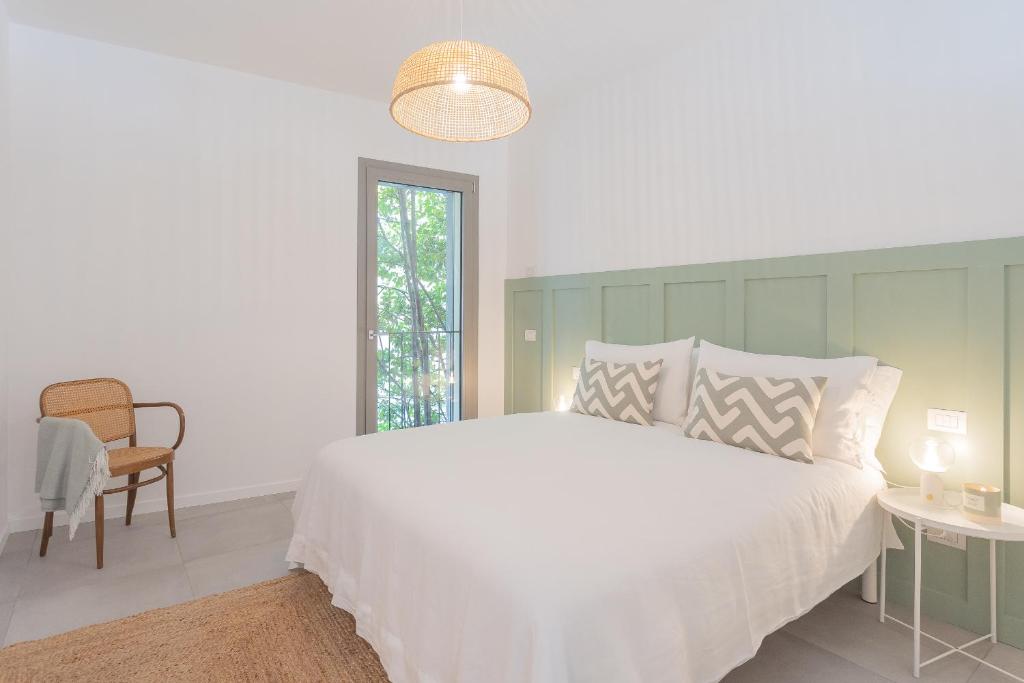 a bedroom with a large white bed and a chair at Ginepro & Salvia Apartments in Como by Rent All Como in Como