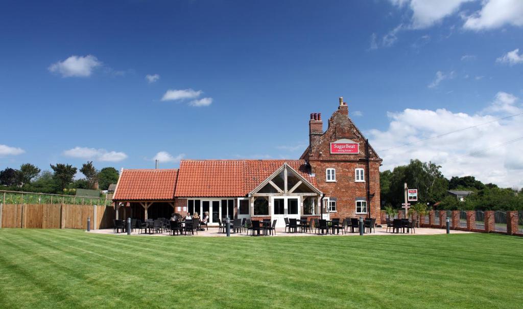 um velho edifício de tijolos com um campo de relva em frente em Sugarbeat Eating House em Norwich