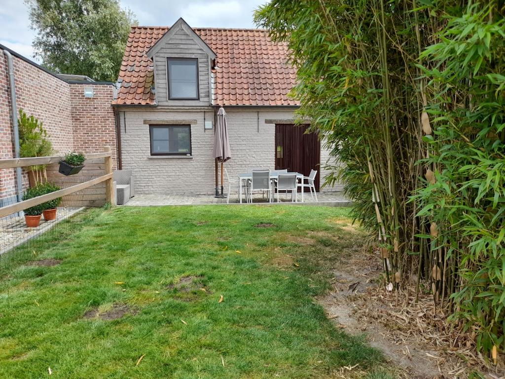 un patio trasero con una casa, una mesa y sillas en Vakantiehuisje 't Morehof, en Oosterzele