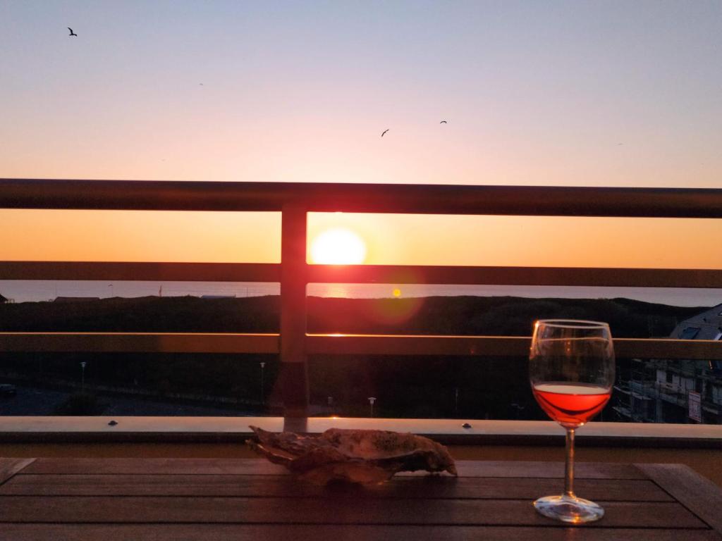 ein Glas Wein auf einem Tisch vor dem Sonnenuntergang in der Unterkunft Haus Brandenburg App 43 in Westerland