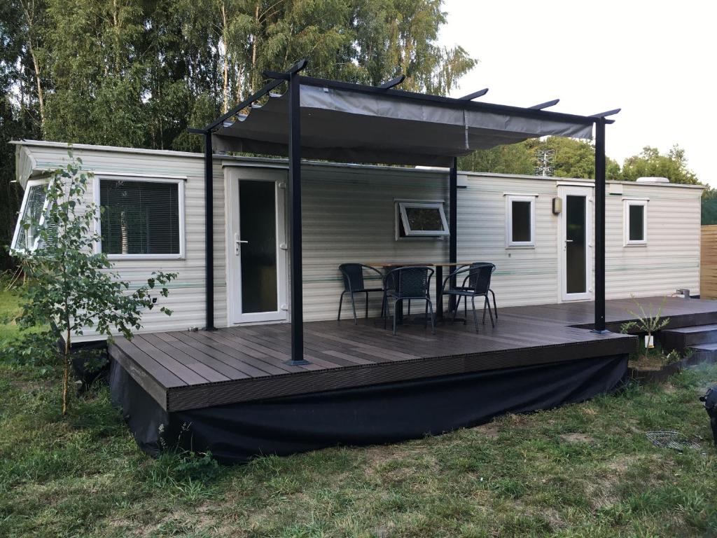a cabin with a deck with a table and chairs at Holender nad Saskiem in Kobyłocha