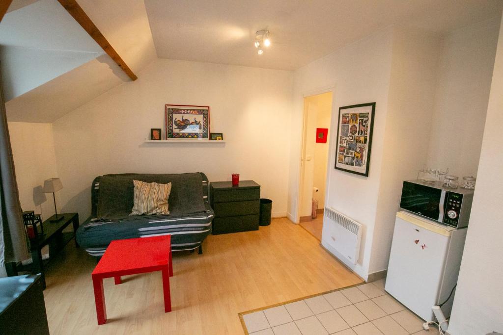 ein Wohnzimmer mit einem Sofa und einem roten Stuhl in der Unterkunft Relais du 21 in Saint-Germain-en-Laye