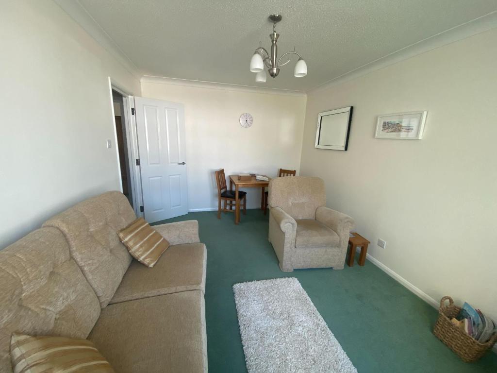 uma sala de estar com um sofá, uma cadeira e uma mesa em The Nook em Sidmouth