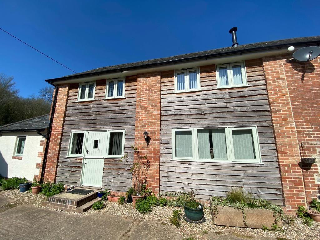 a brick house with a white door and windows at Guernsey Cottage in Ottery Saint Mary