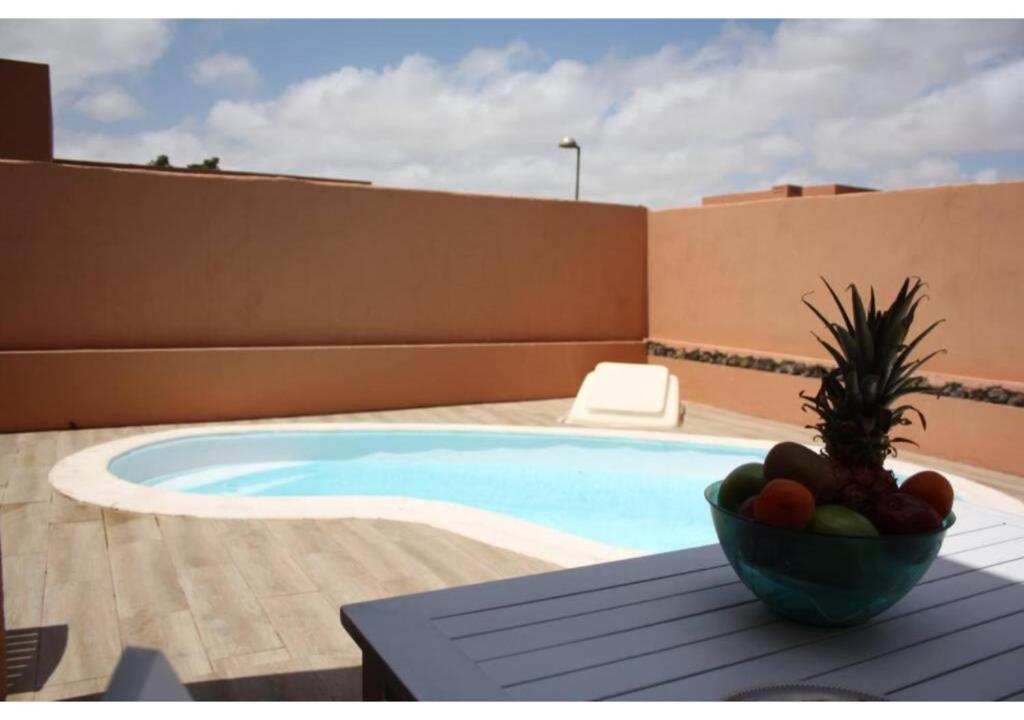 a bowl of fruit sitting on a table next to a swimming pool at Anahi Homes Corralejo - Villa Drago 12 in La Oliva