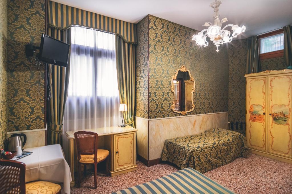 a bedroom with a bed and a desk and a window at Hotel Al Malcanton in Venice