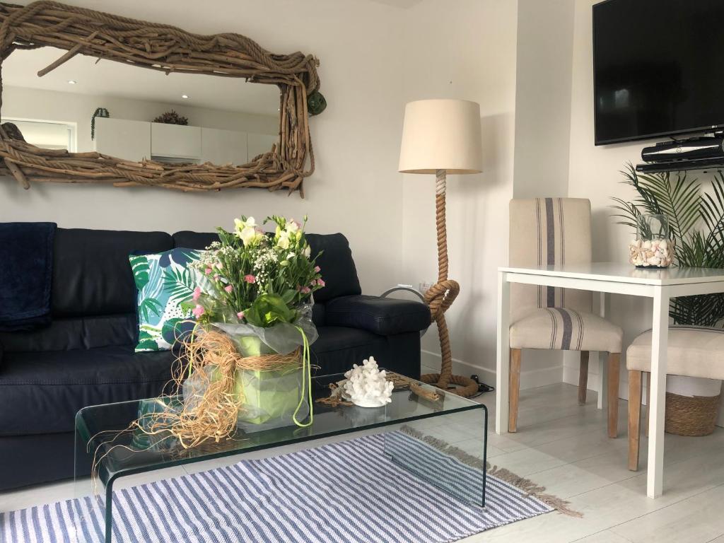 uma sala de estar com um sofá e uma mesa com flores em Ocean Drive Deluxe Apartment ground floor Brean with a complimentary Tray em Brean