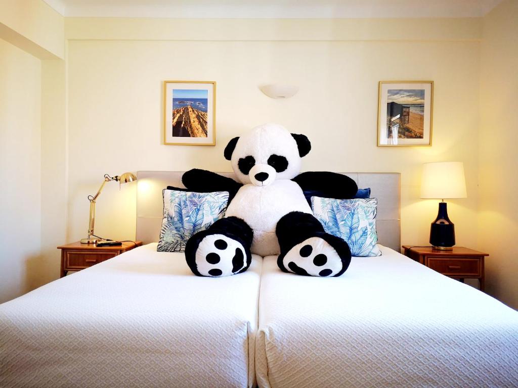 a stuffed panda bear sitting on top of a bed at The Blue Bamboo Hotel - Duna Parque Group - "Ex Casa dos Arcos" in Vila Nova de Milfontes