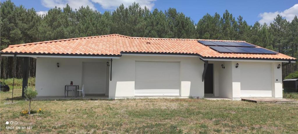 a small white house with solar panels on the roof at chambre au pied de la forêt in Onesse-et-Laharie