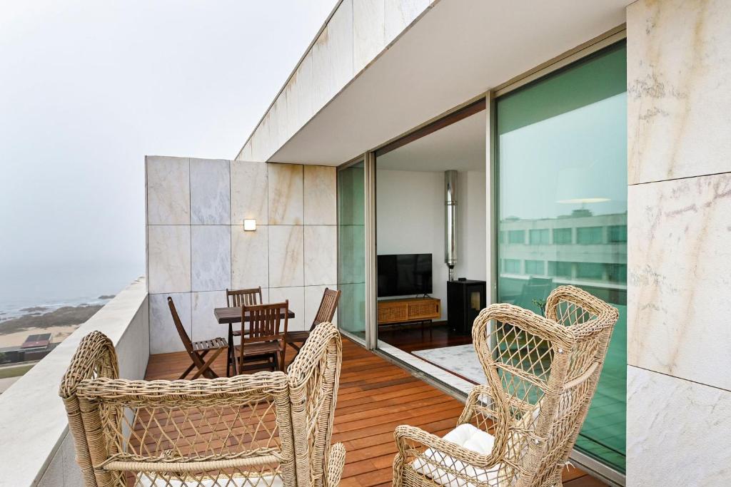 uma varanda com cadeiras, uma mesa e uma televisão em Leça Front Beach Luxury Penthouse em Leça da Palmeira