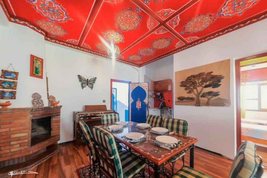 Casa Plasa Grande CHEFCHAOUEN في شفشاون: غرفة طعام مع طاولة وسقف احمر