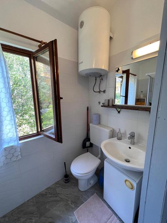łazienka z toaletą, umywalką i oknem w obiekcie Apartments Valentinovo w mieście Klenovica