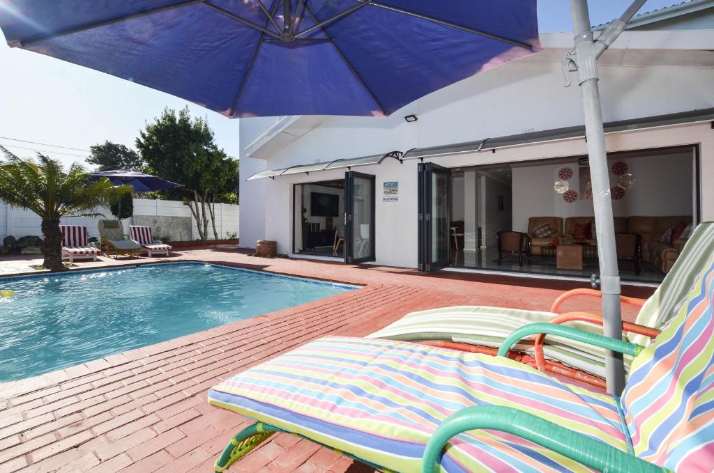 a swimming pool with two lawn chairs and an umbrella at Casa Milner Guest House in Cape Town