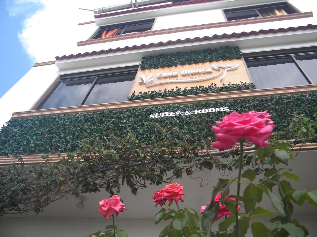 un edificio con un cartel y flores delante de él en Casa Blanca Puerto López, en Puerto López