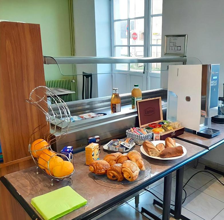 a table with a bunch of bread and pastries on it at Hôtel du Cerf in La Guerche-sur-lʼAubois