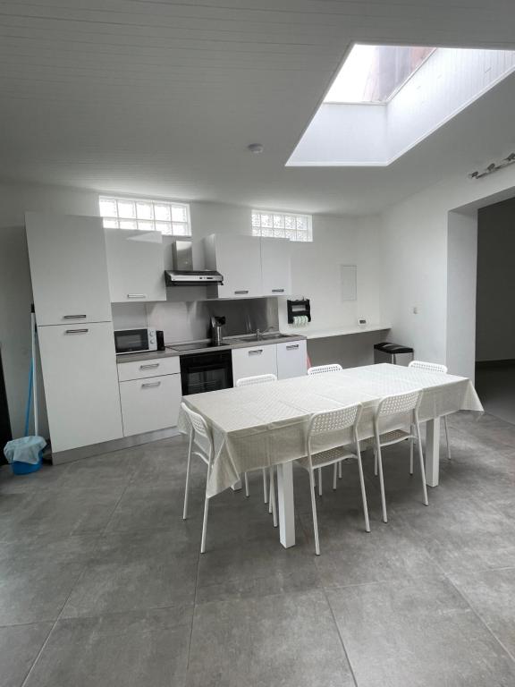 uma cozinha branca com uma mesa e cadeiras brancas em Maison Pétria em Fontaine-lʼÉvêque