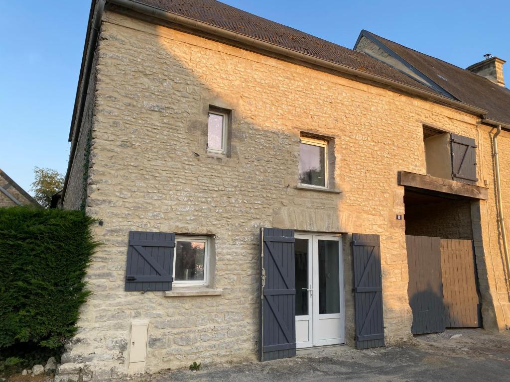 une vieille maison en briques avec volets noirs dans l'établissement Le saint Exupery, à Saint-Vigor-le-Grand
