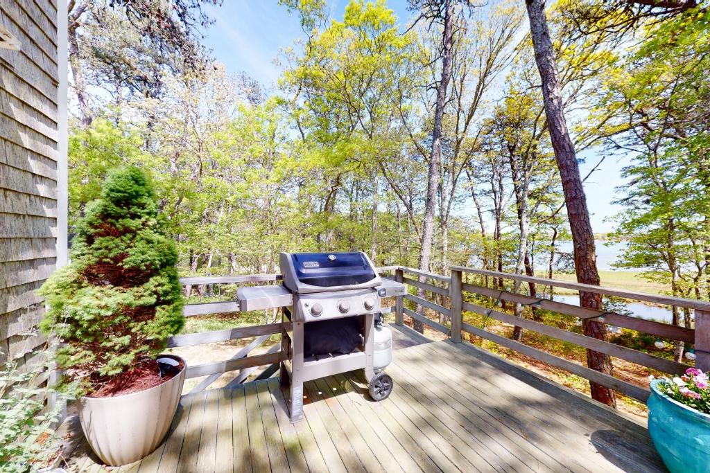 a barbecue grill on a wooden deck next to a fence at Dennis Port Delight in Dennis Port