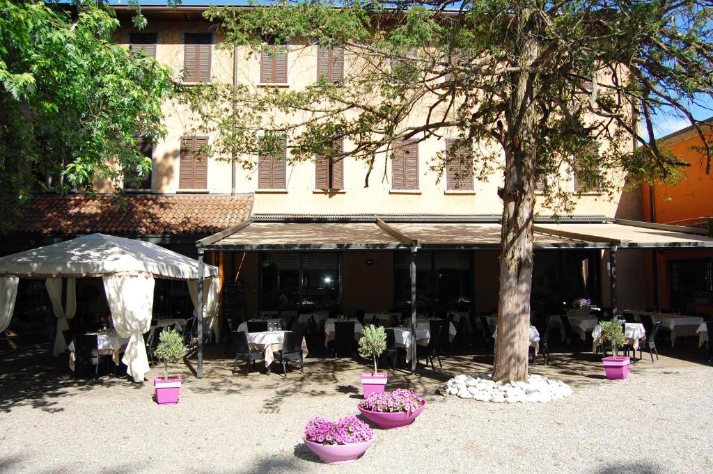 ein Gebäude mit Tischen, Stühlen und einem Baum in der Unterkunft Albergo Ristorante Sant'Eustorgio in Arcore