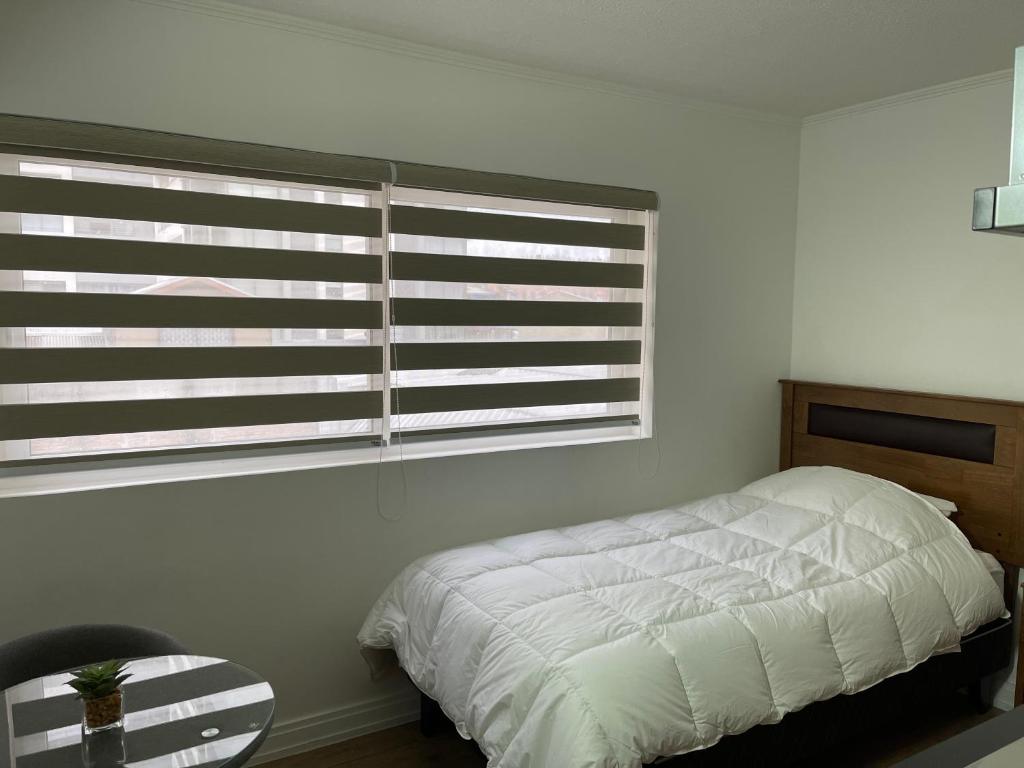 - une chambre avec un lit blanc et une fenêtre dans l'établissement TinyApartments - estudio pleno centro Concepción, à Concepción